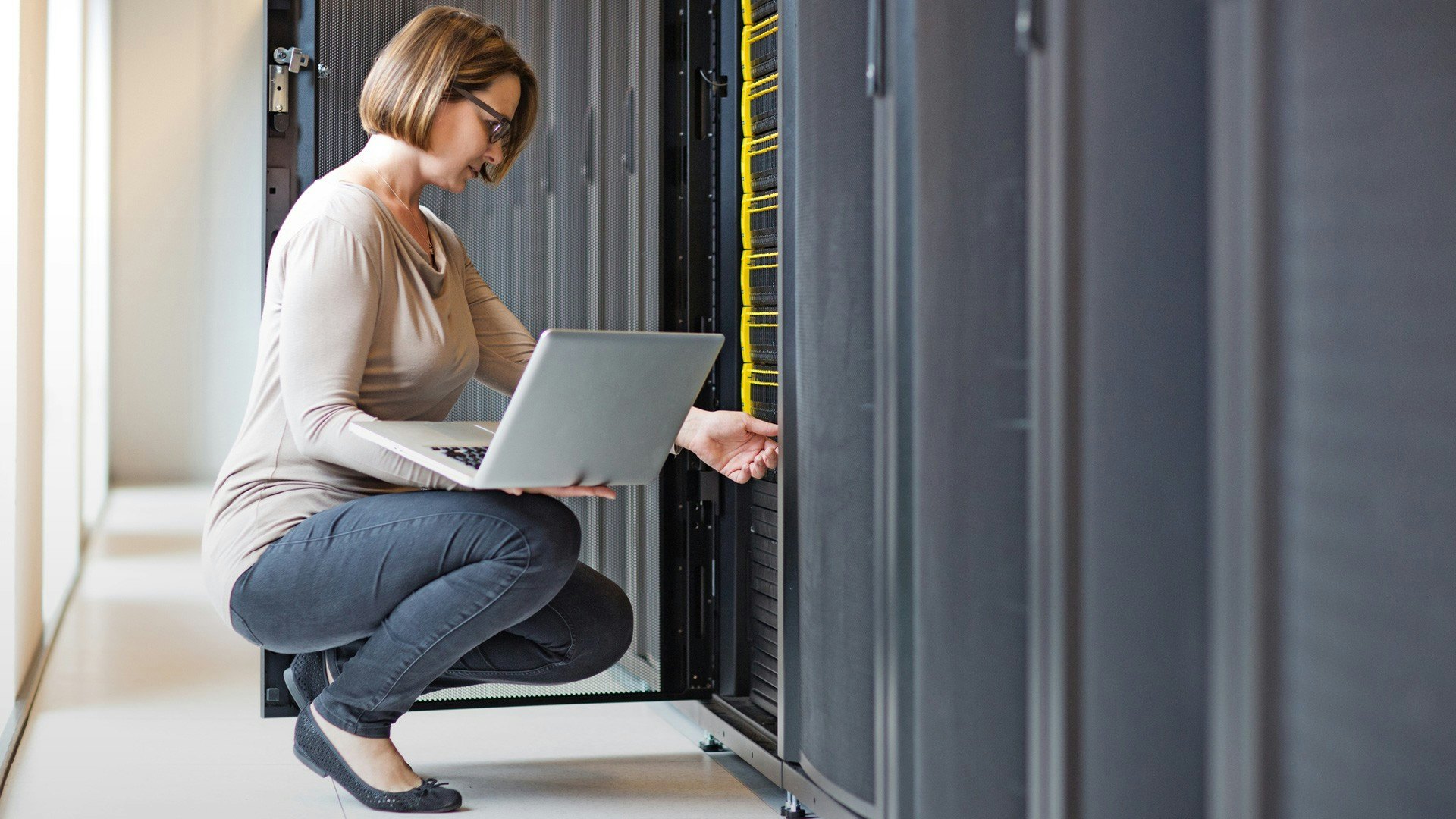 blonde woman with computer crouching down