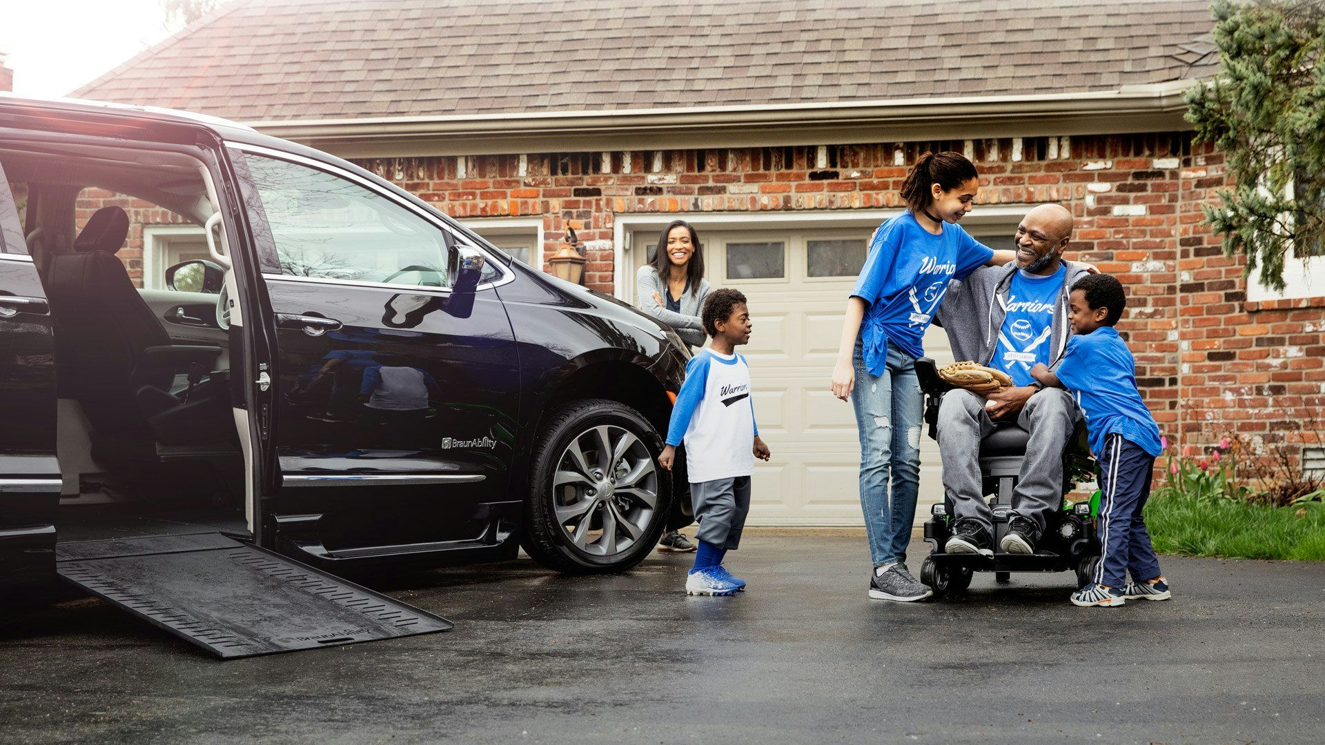 man in wheel chair with family getting out of braunability mini van